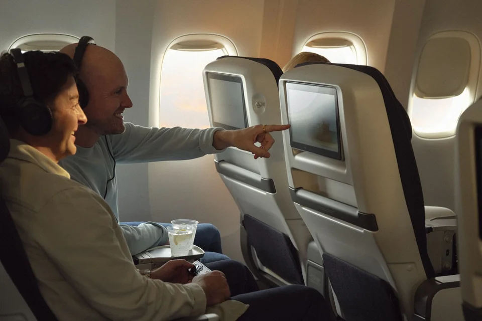 Pasażerowie korzystający z ekranów w World Traveller Plus